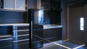 Una cocina moderna con un refrigerador negro, electrodomésticos de acero inoxidable y un ventanal que proporciona luz natural.