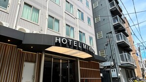 Entrada de hotel con fachada moderna, grandes puertas de vidrio y un letrero que dice "HOTELMIKADO".