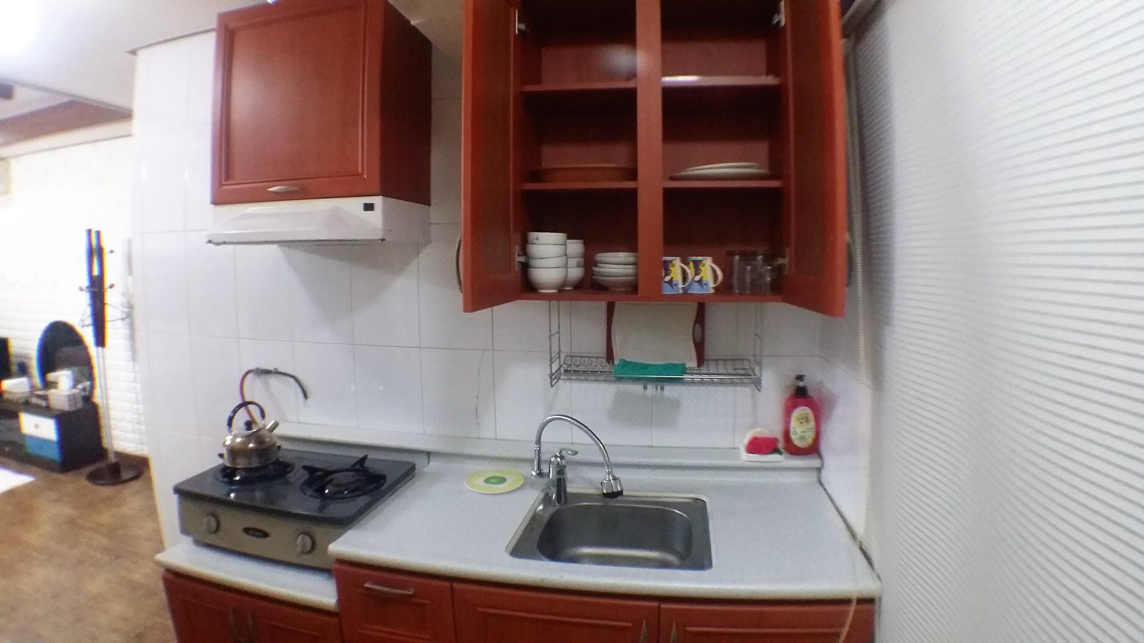 A compact kitchen with a gas stove, a sink, and wooden cabinets.