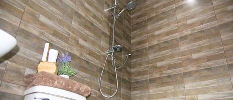 A bathroom with a shower, toilet, and a sink area.