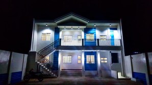 Un edificio de dos pisos con una escalera central, múltiples ventanas y un balcón.
