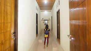 A hallway with wooden doors and a tiled floor. - Dorme Tree (Labuan Bajo)