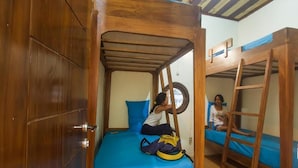 A bunk bed room with a wooden ladder and a circular window. - Dorme Tree (Labuan Bajo)