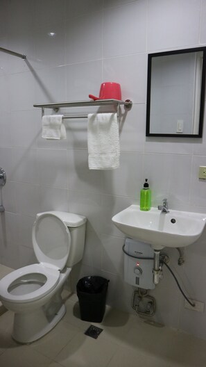 A bathroom with a toilet, sink, and a mirror. - Doniti Suites and Events Place (Mandaluyong)