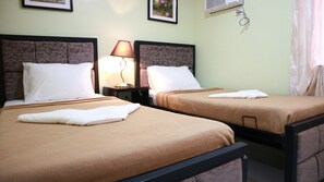 Two twin beds with brown bedding, a bedside lamp, and a wall-mounted air conditioner. - Doniti Suites and Events Place (Mandaluyong)