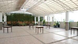 A spacious indoor area with a high ceiling and a green wall covered in plants. There are several tables and chairs arranged for seating. - Doniti Suites and Events Place (Mandaluyong)