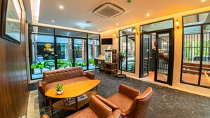 A modern interior with leather seating, a wooden table, and large windows offering views of the outdoors. - J4 Hotel Samui (Koh Samui)
