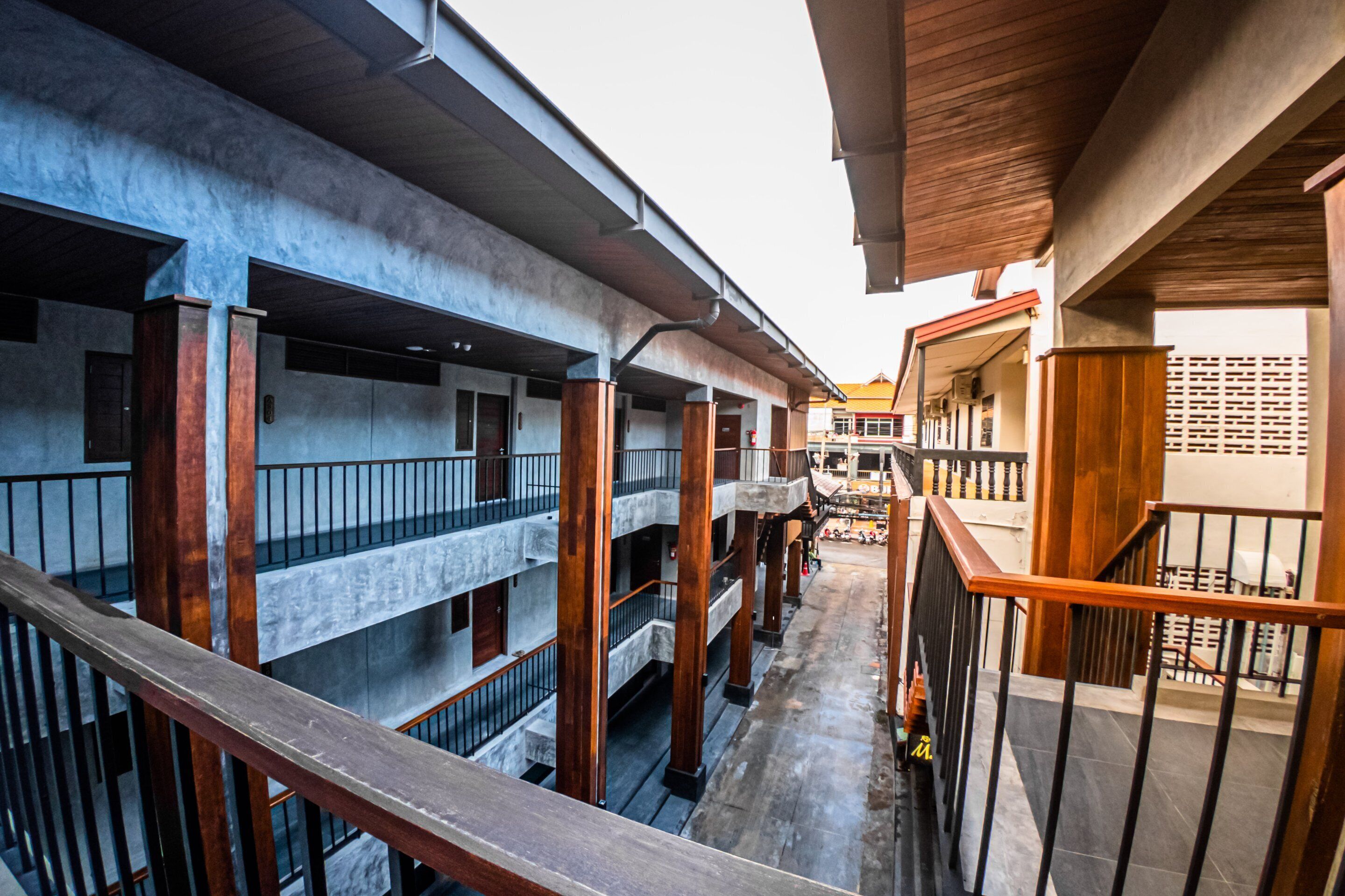 Un immeuble à plusieurs étages doté de balcons, de rampes en bois et d’une façade en béton.