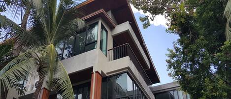 A modern multi-story building with large windows and a balcony.