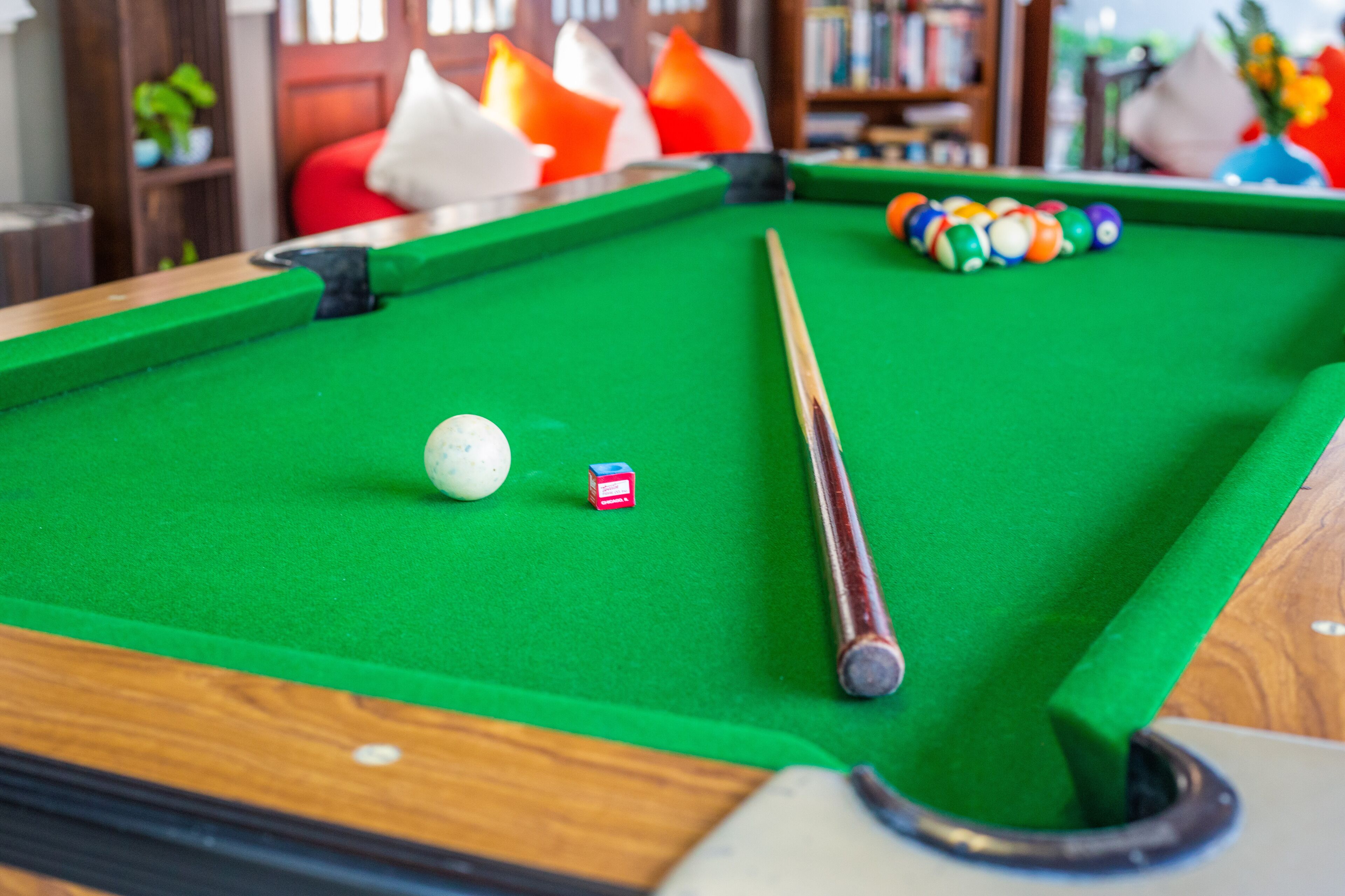 Une table de billard avec un queue, une boule blanche et des boules de couleurs.