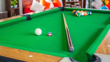 Une table de billard avec un queue, une boule blanche et des boules de couleurs.