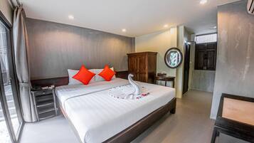 A hotel room with a large bed, a wooden headboard, a nightstand, a mirror, and a wardrobe.