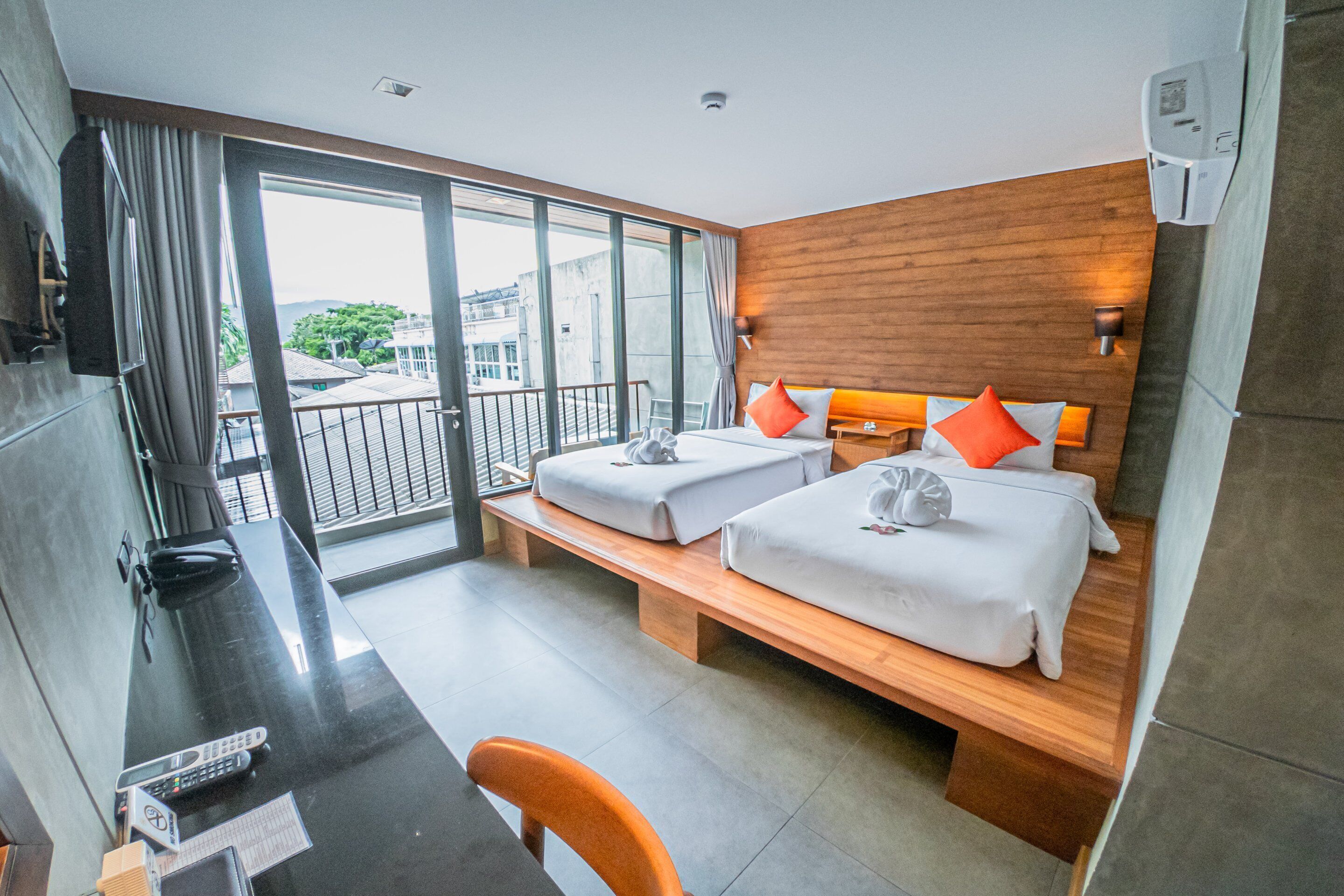 Une chambre d’hôtel avec un balcon, deux lits, un bureau et une chaise.