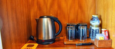 A kitchenette with a Philips electric kettle, a water bottle, a glass jar, a mug, and a coffee maker.