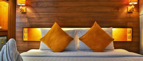 A hotel room with a wooden headboard, two pillows, and wall-mounted lamps.