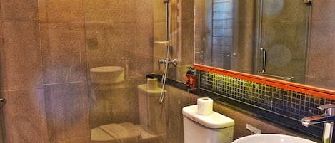 A modern bathroom with a glass-enclosed shower, a toilet, and a sink.