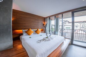 Una habitación de hotel moderna con una cama grande, paredes de panel de madera y un balcón con vista a la ciudad.
