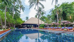 A swimming pool with tiled blue and green patterns, surrounded by palm trees and lounge chairs with umbrellas. - J4 Hotel Samui (Koh Samui)