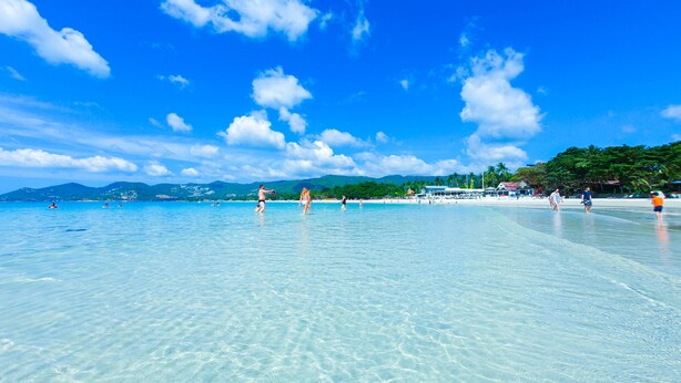 A clear blue sea with people swimming and walking on the beach. - J4 Hotel Samui (Koh Samui)