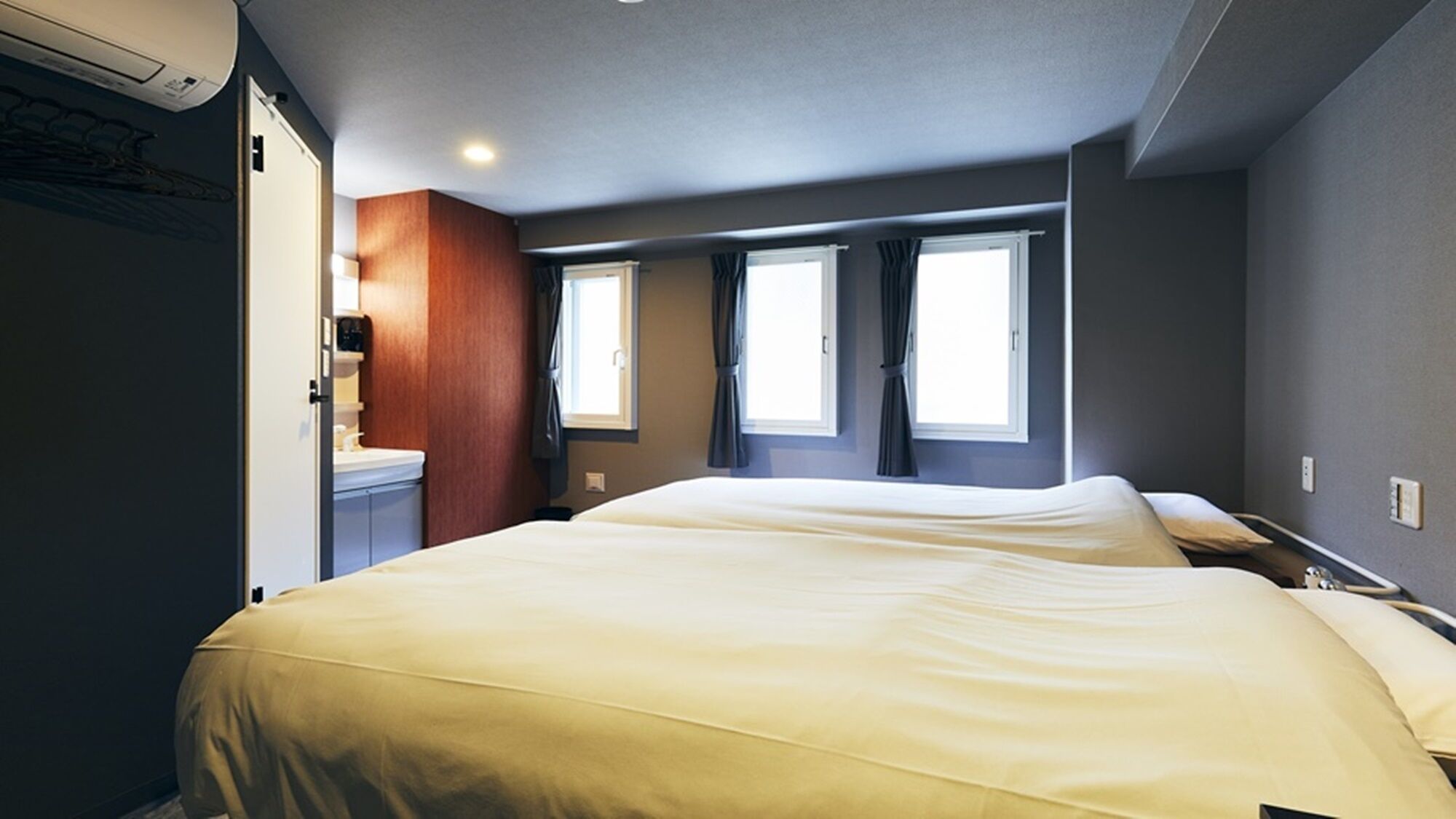 A hotel room with two beds, a bathroom, and a window.