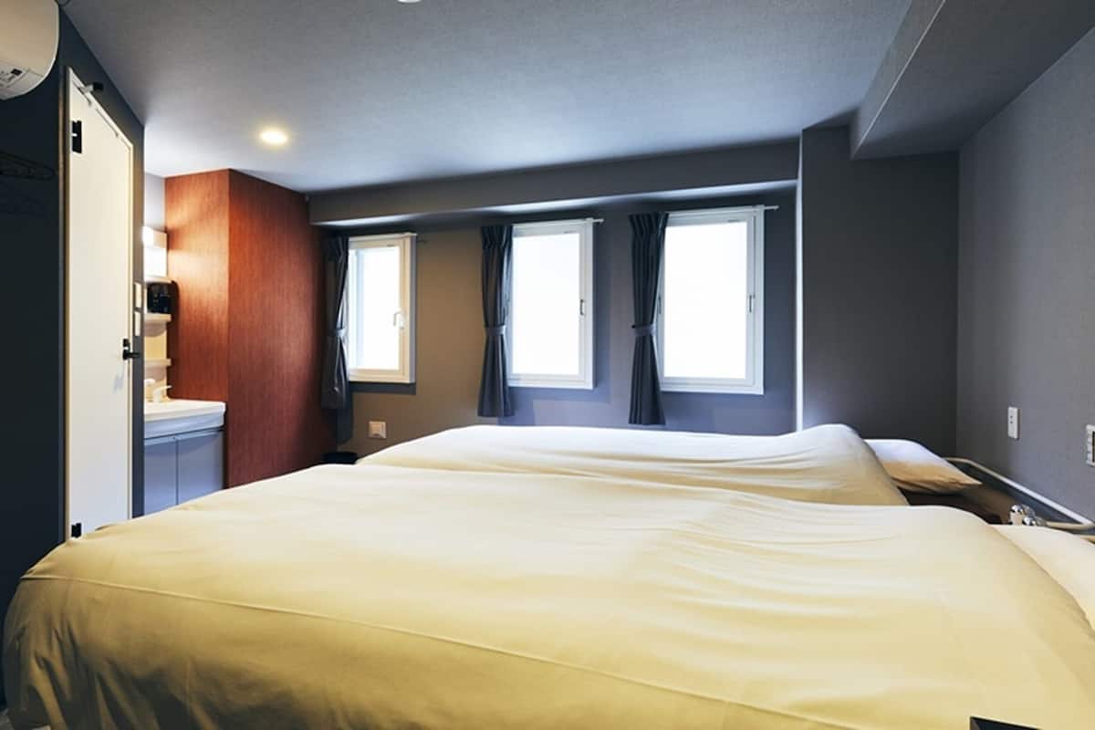 Habitación de hotel con dos camas, baño y ventana.
