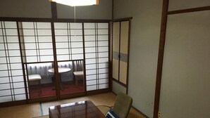 A traditional Japanese room with tatami flooring, a low wooden table, a chair, and a sliding shoji screen. - Kinreisou (Hakone)