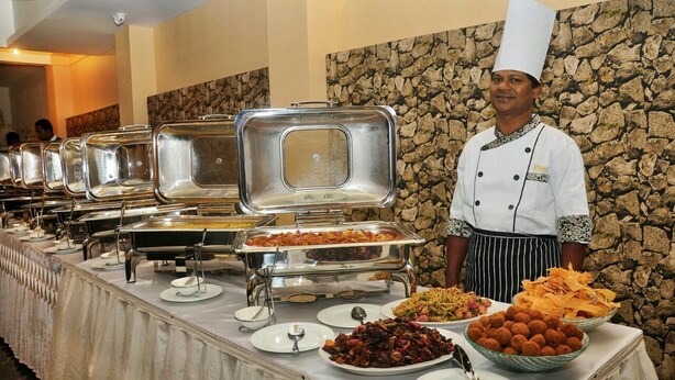 Mesa de buffet con diversos alimentos y un chef de pie.