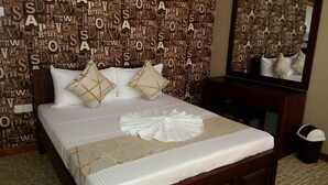 Una habitación de hotel con cama, almohadas, una mesita de noche y un espejo.