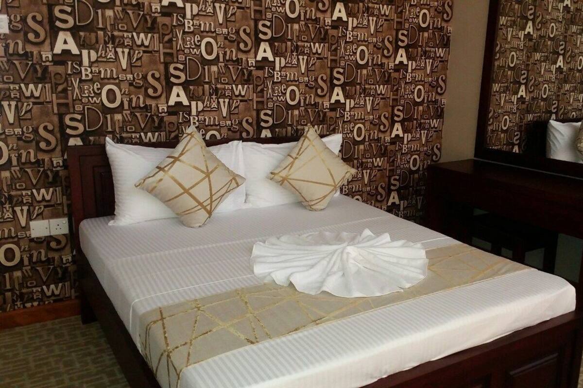 A hotel room with a bed, pillows, a bedside table, and a mirror.
