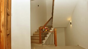 Una escalera con barandas de madera y un arreglo floral en la parte superior.