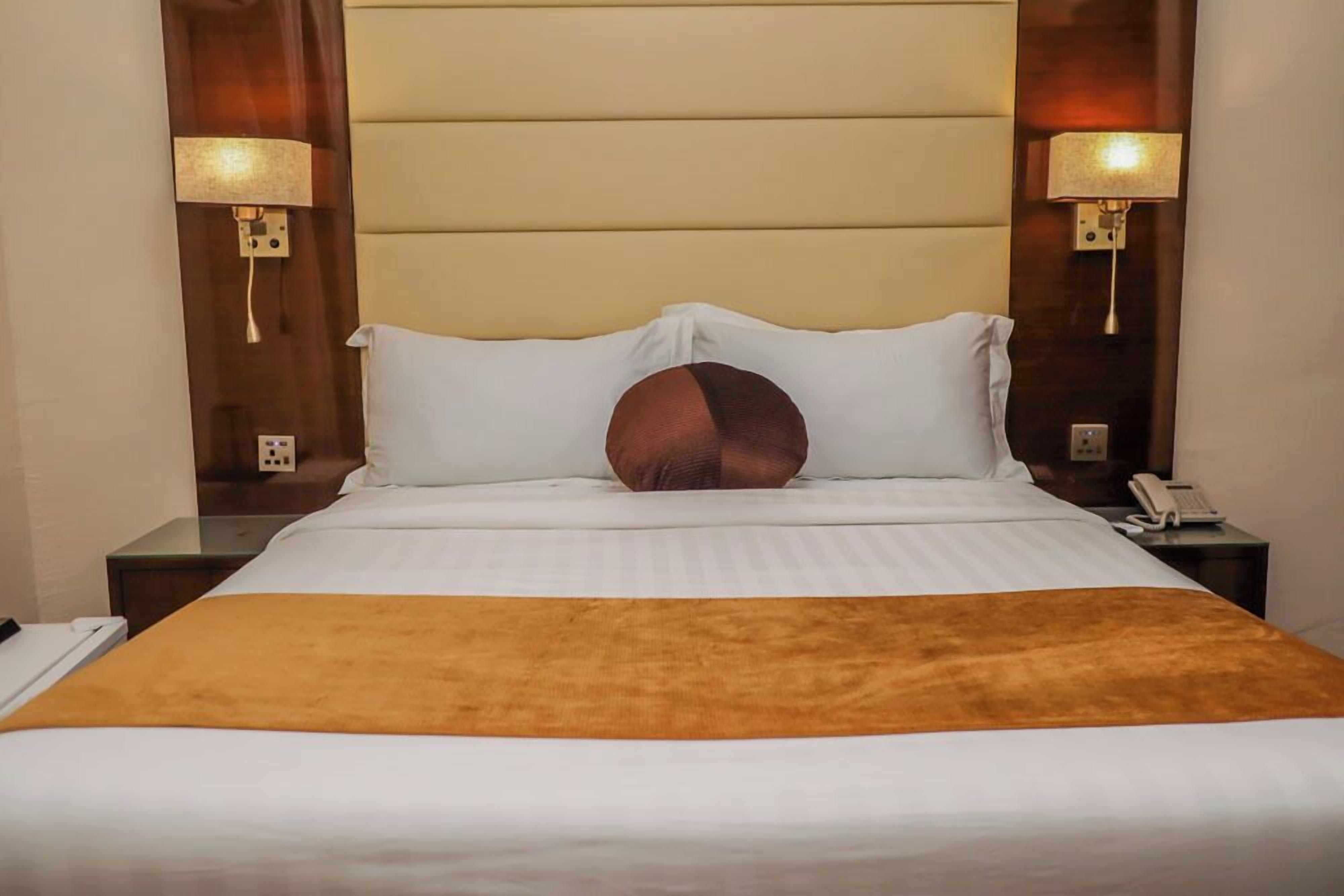 Une chambre d’hôtel comprenant un lit, deux tables de chevet, une commode, une lampe et un téléphone.