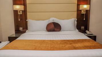 Une chambre d’hôtel comprenant un lit, deux tables de chevet, une commode, une lampe et un téléphone.