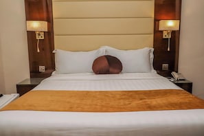 Una habitación de hotel con una cama, dos mesitas de noche, una lámpara y un teléfono.