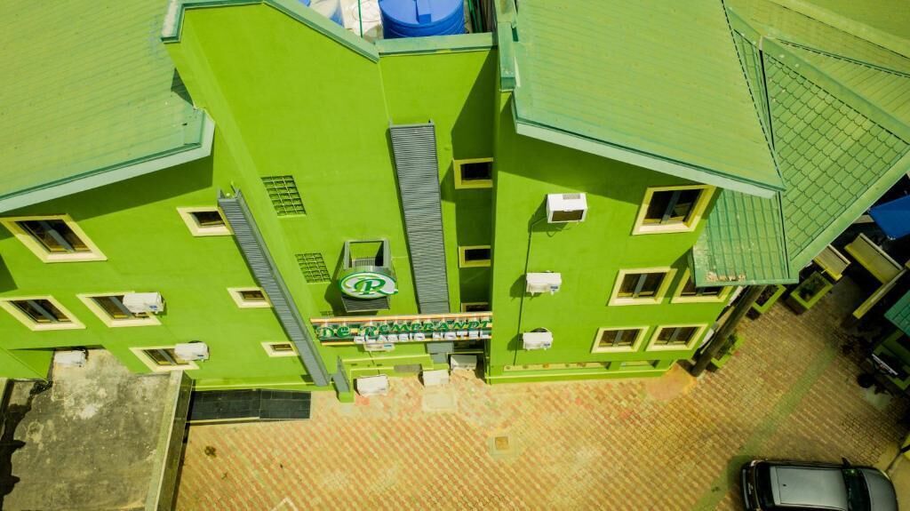 A multi-story building with a green facade, multiple windows, and a visible sign with a logo.