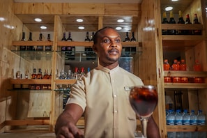 A wooden interior with shelves of bottles and a person holding a wine glass.