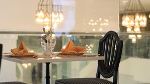 Una mesa de comedor dispuesta con un florero, dos servilletas dobladas y un vaso de agua.