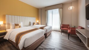 Habitación de hotel con dos camas, un escritorio, una silla y un televisor.