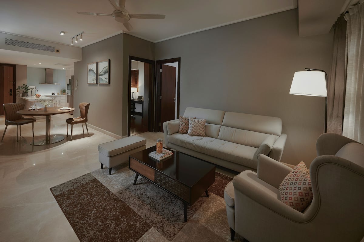 A modern living room with a sofa, armchairs, a coffee table, and a dining area with a table and chairs.