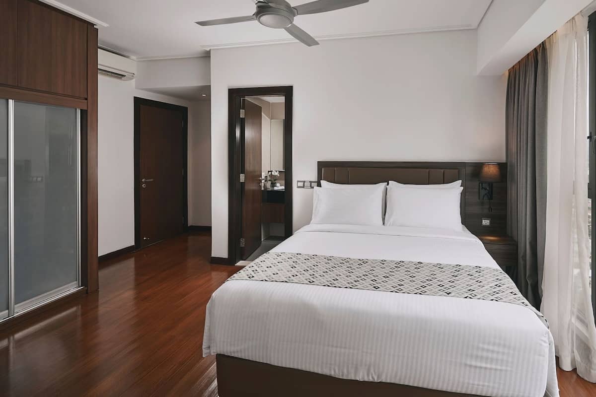 A hotel room with a large bed, a ceiling fan, a view of the city, and a wardrobe.