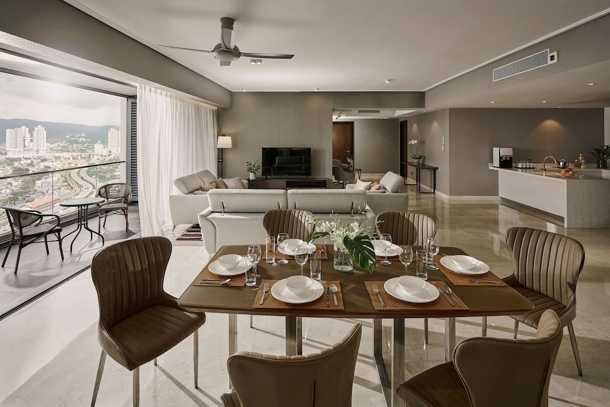 A modern dining area with a large table set for six, a sofa in the background, and a city view through large windows.