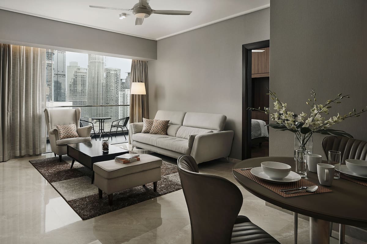 A modern living room with a sofa, armchairs, a coffee table, and a dining area with a table and chairs.