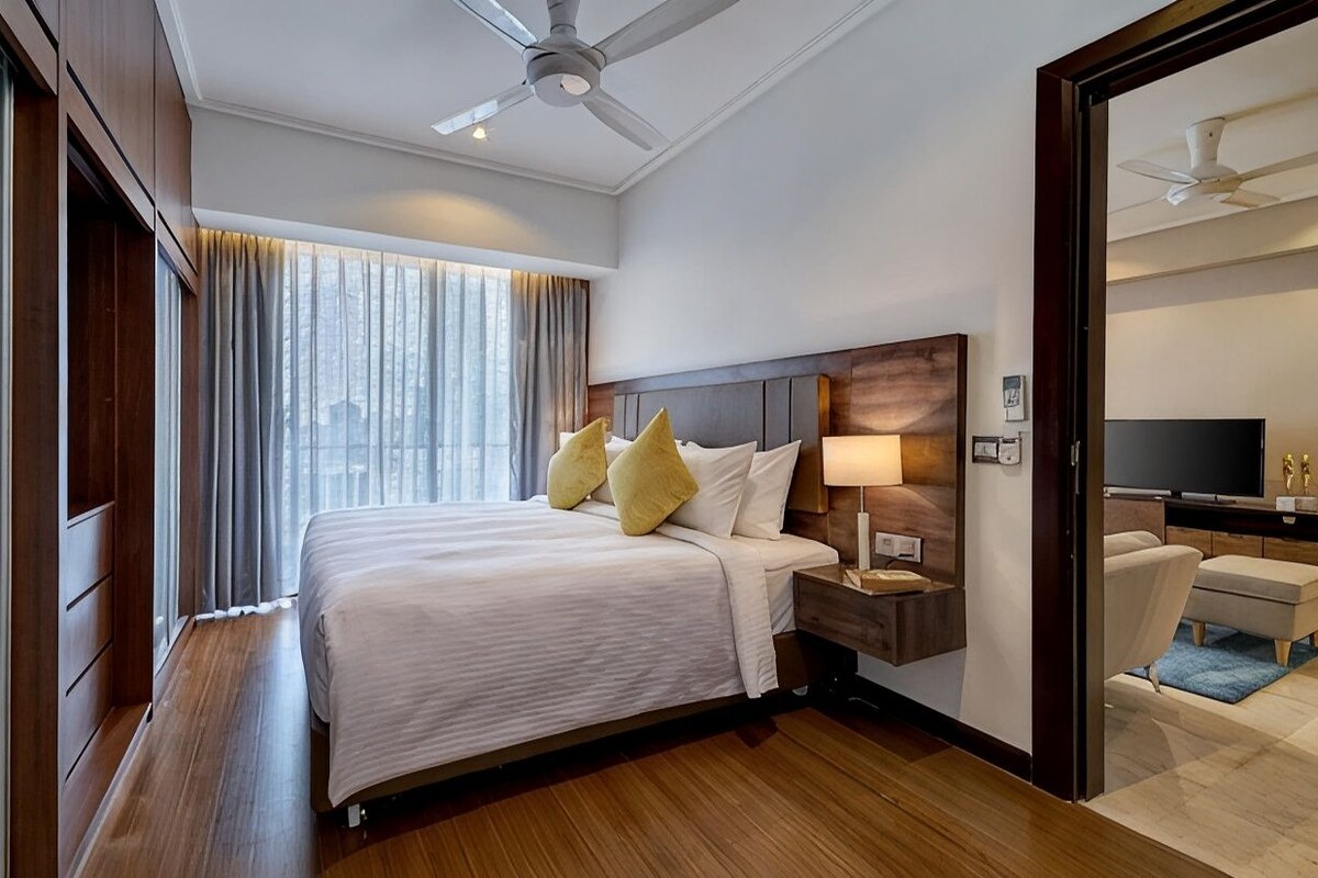 A hotel room with a bed, bedside table, lamp, and a television.