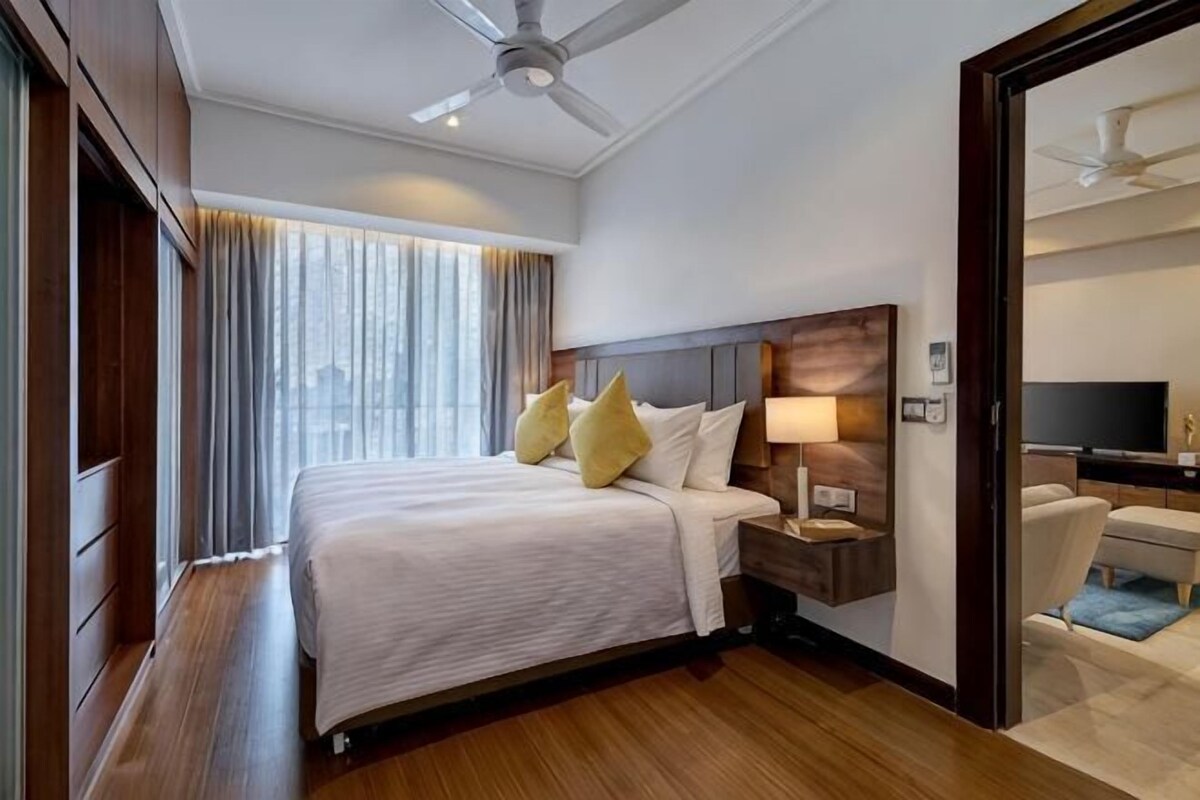 A hotel room with a bed, bedside table, lamp, and a TV.