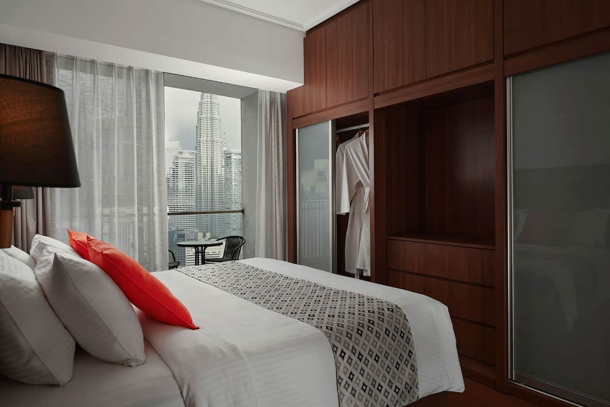 A hotel room with a bed, a table, and a view of a cityscape.