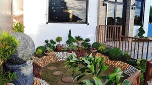 A well-maintained garden with various plants and decorative stones, a stone sculpture, and a wooden fence. - Casa Del Camba Hotel and Restaurant near Hundred Islands (Alaminos)