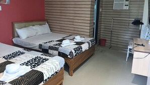 A hotel room with two beds, a desk, and an air conditioning unit. - Casa Del Camba Hotel and Restaurant near Hundred Islands (Alaminos)