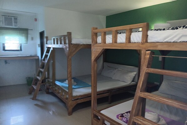 Habitación con literas, una escalera, un ventanal pequeño y pared verde.