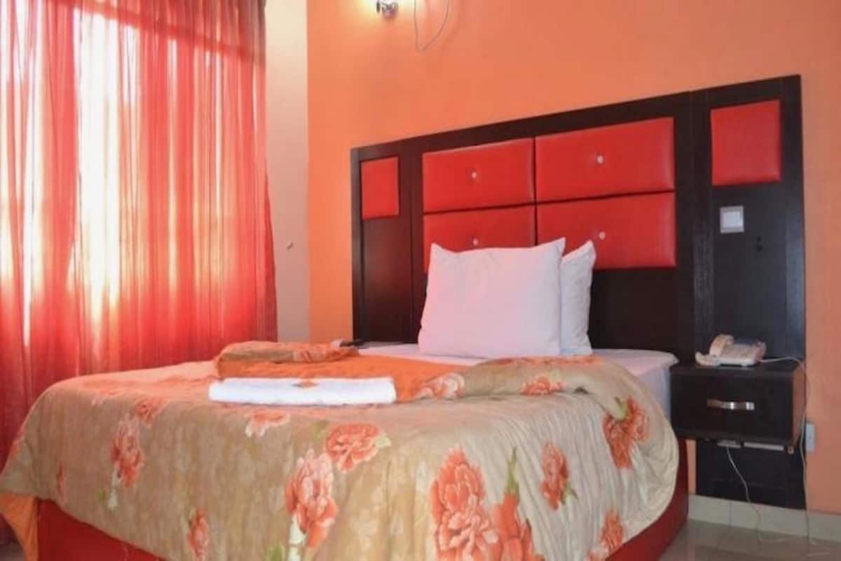Una habitación de hotel con una cama, una mesita de noche y un teléfono.