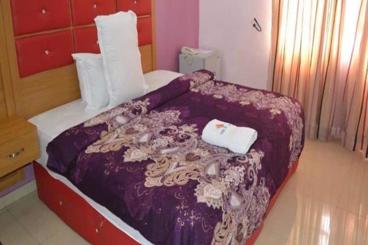 Un dormitorio con cabecera roja, colcha morada y almohada blanca.