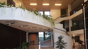 Un vaste atrium doté d’un escalier central, de plantes en pot et d’un design moderne.